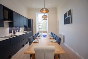 Une cuisine moderne avec des meubles de couleur sombre, une table à manger en bois et un centre de table composé d’un bol bleu.