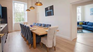 A dining area with a wooden table and chairs, a television, and a sofa in the adjacent room.