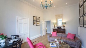 Een woonkamer met een eetgedeelte, een bank, een bijzettafeltje en een kroonluchter.