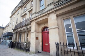 A building with a red door, a black metal fence, and a balcony. - Stylish City Centre Apartment  (MSB) (Bath)
