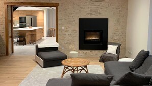 Een moderne woonkamer met een hoekbank, een klein rond tafeltje en een open haard.