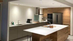 Een moderne keuken met een centraal eiland, barkrukken en inbouwapparatuur.