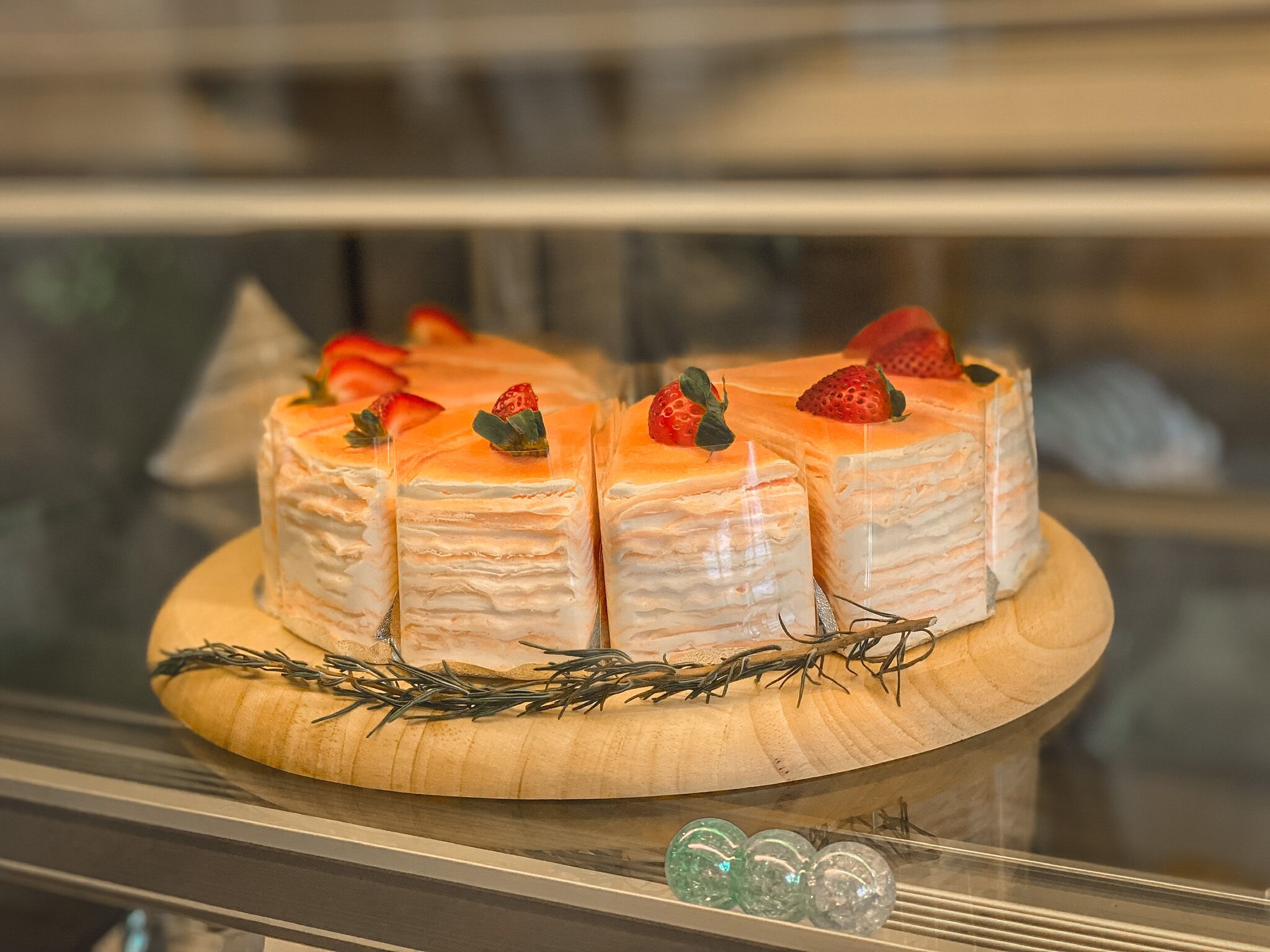 Un présentoir de desserts avec des gâteaux à plusieurs couches, garnis de fraises et décorés de romarin.