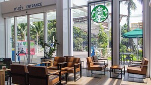 A Starbucks inside a building with large windows, seating area, and entrance sign. - 75/2 Residence Hua Hin (Hua Hin)