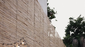 Un edificio con un muro texturizado y un camino que lleva a una puerta.