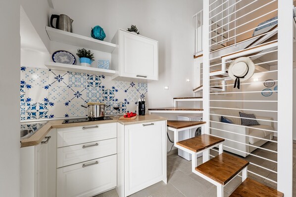 Une cuisine moderne avec des armoires blanches, un pare-feu bleu à motifs et des comptoirs en bois.