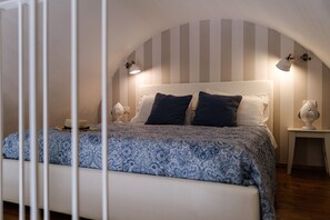 Une chambre à coucher avec un lit, deux tables de chevet et un mur recouvert d’un papier peint à rayures.