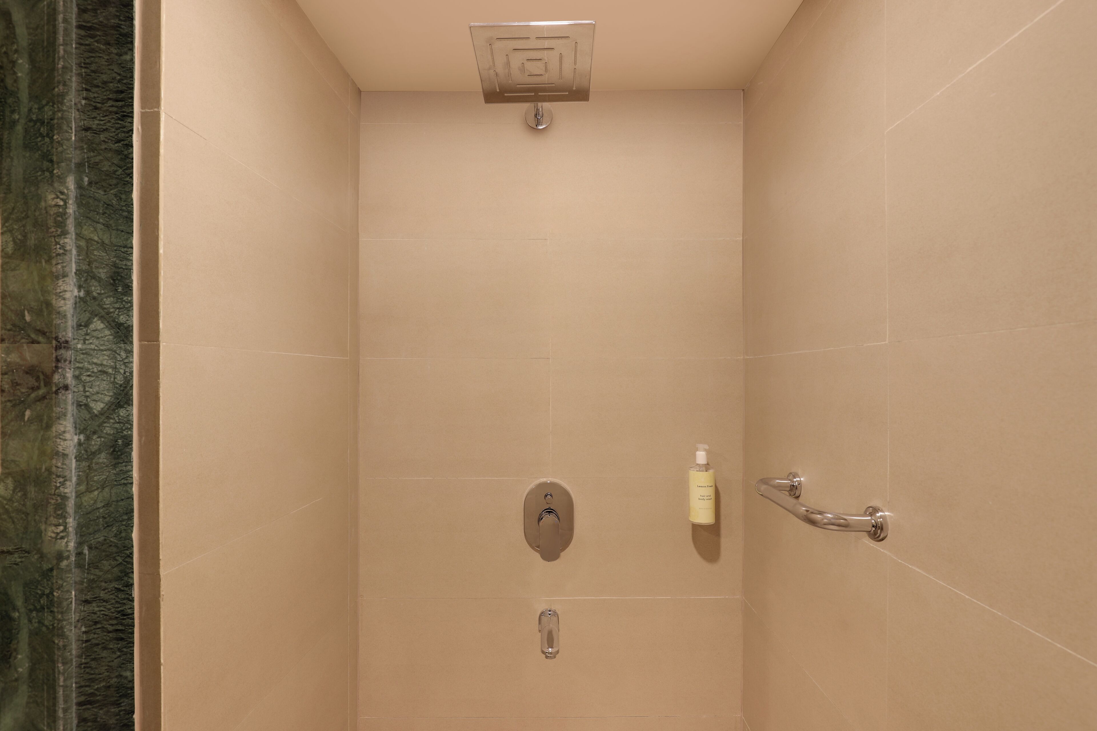 Ducha con cabezal de ducha de mano, dispensador de jabón de mano y grifo instalado en la pared.