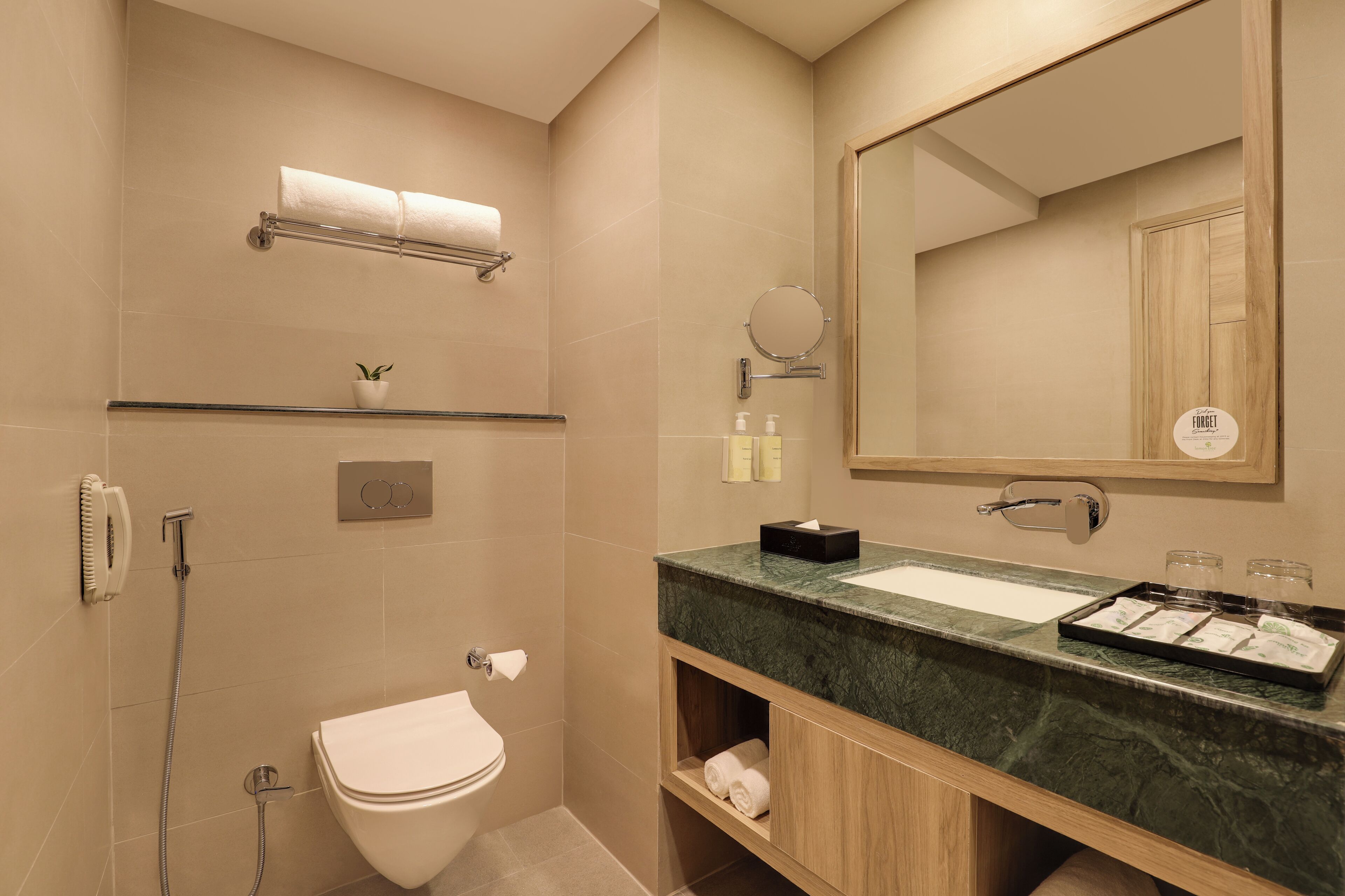 A modern bathroom with a toilet, sink, and shower. There is a towel rack, a mirror, and a shelf with toiletries.