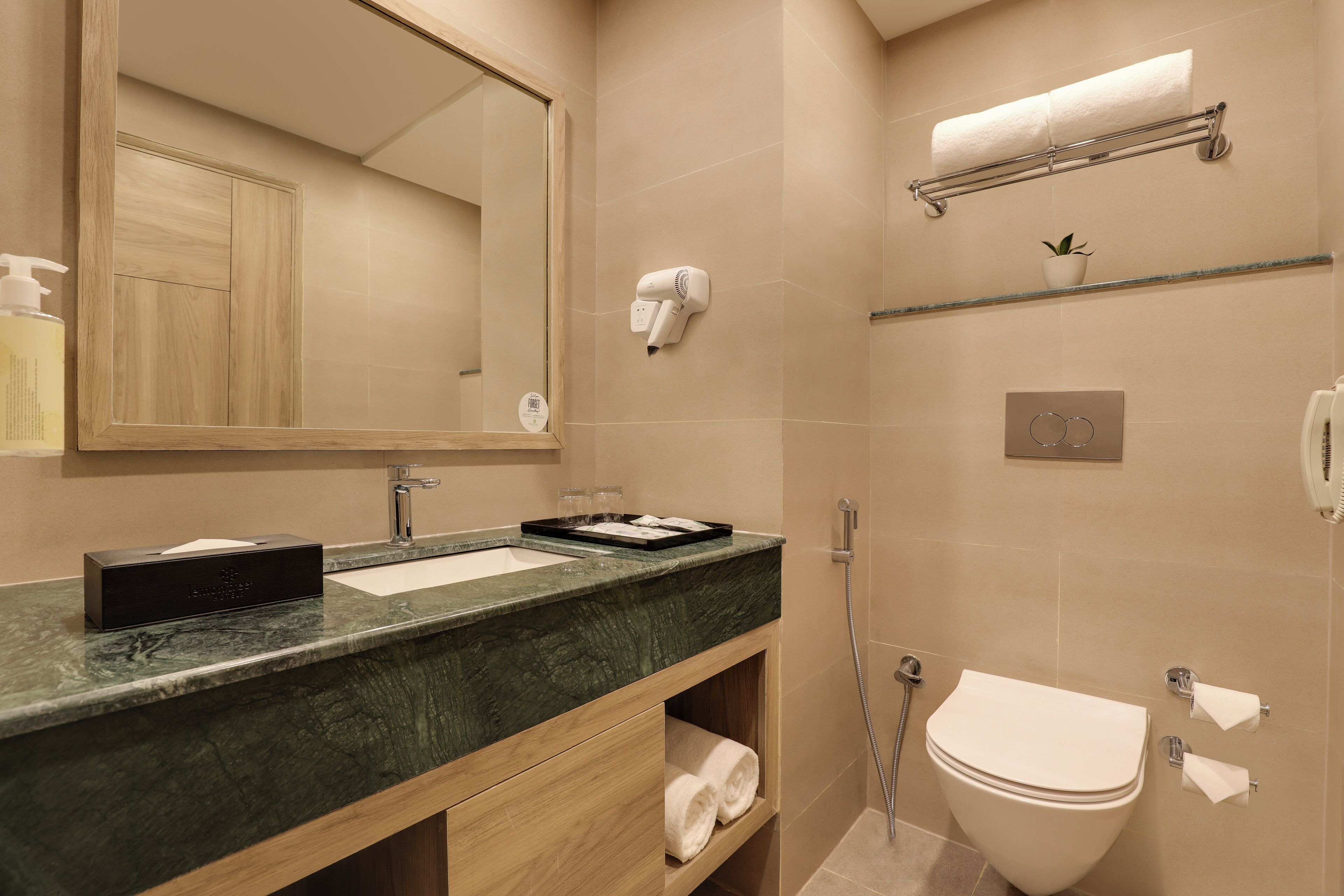 A modern bathroom with a marble sink, a large mirror, a hairdryer, and a toilet.