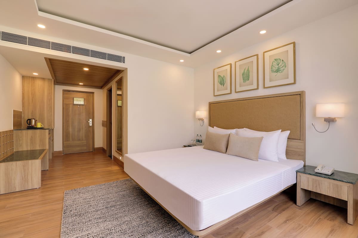 A hotel room with a large bed, bedside tables, a desk, and a shower area.