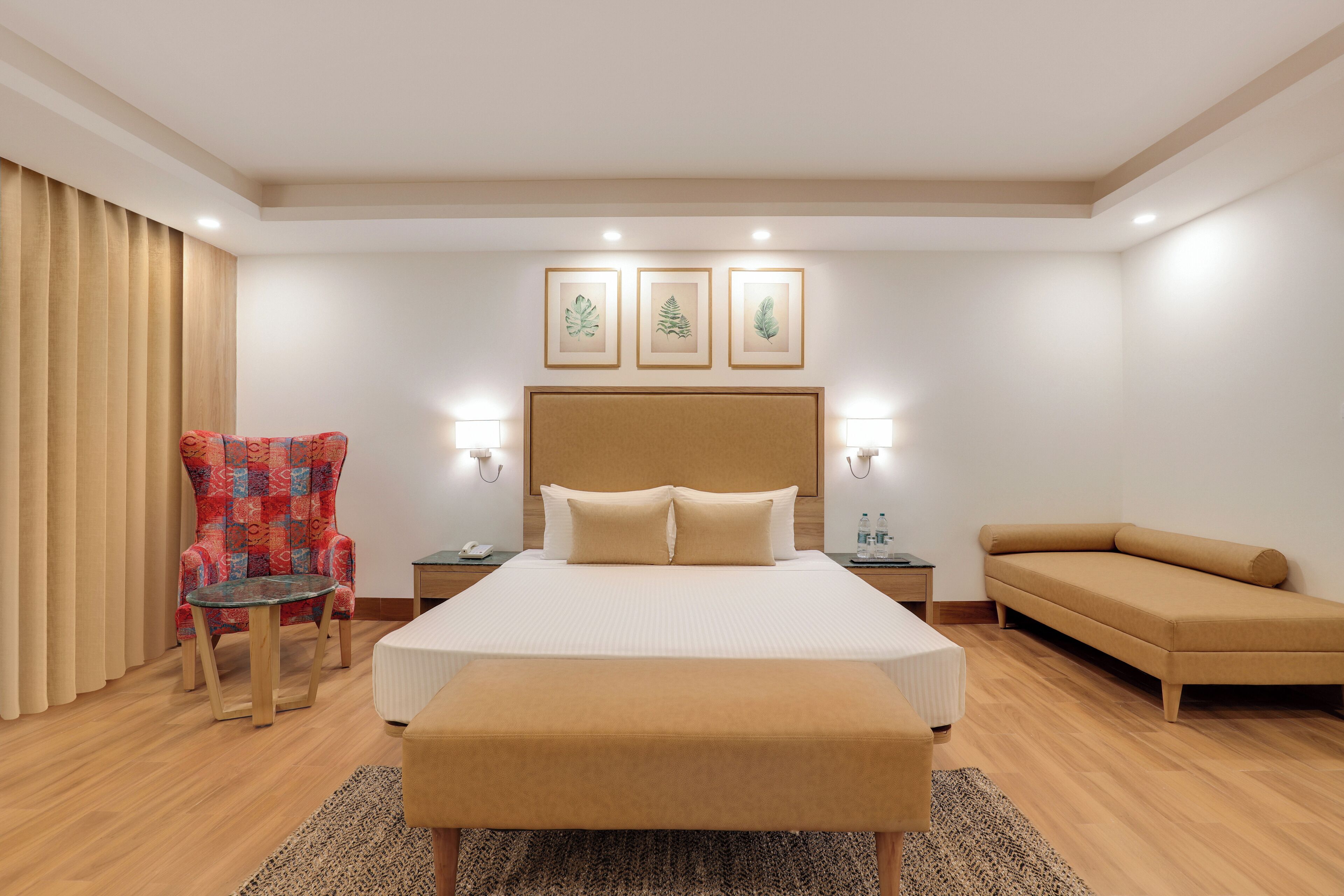 Habitación de hotel con una cama grande, una silla, un sofá y una mesita.