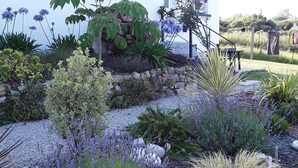 A white house with a blue roof, surrounded by a garden with various plants and flowers. - Location Maison Plein Pied 6 Personnes 800 ml de la Plage et du Port a Pied (Camaret-sur-Mer)