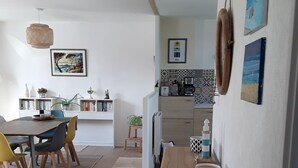 A modern kitchen with a dining area, featuring a wooden table, chairs, and a white cabinet. - Location Maison Plein Pied 6 Personnes 800 ml de la Plage et du Port a Pied (Camaret-sur-Mer)