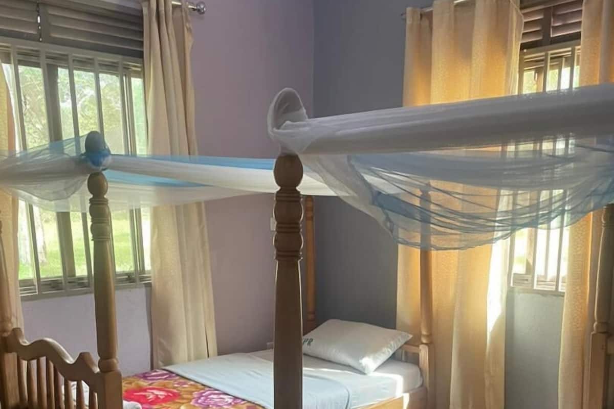 Een kamer met twee houten bedden, waarvan er één een hemelbed is.