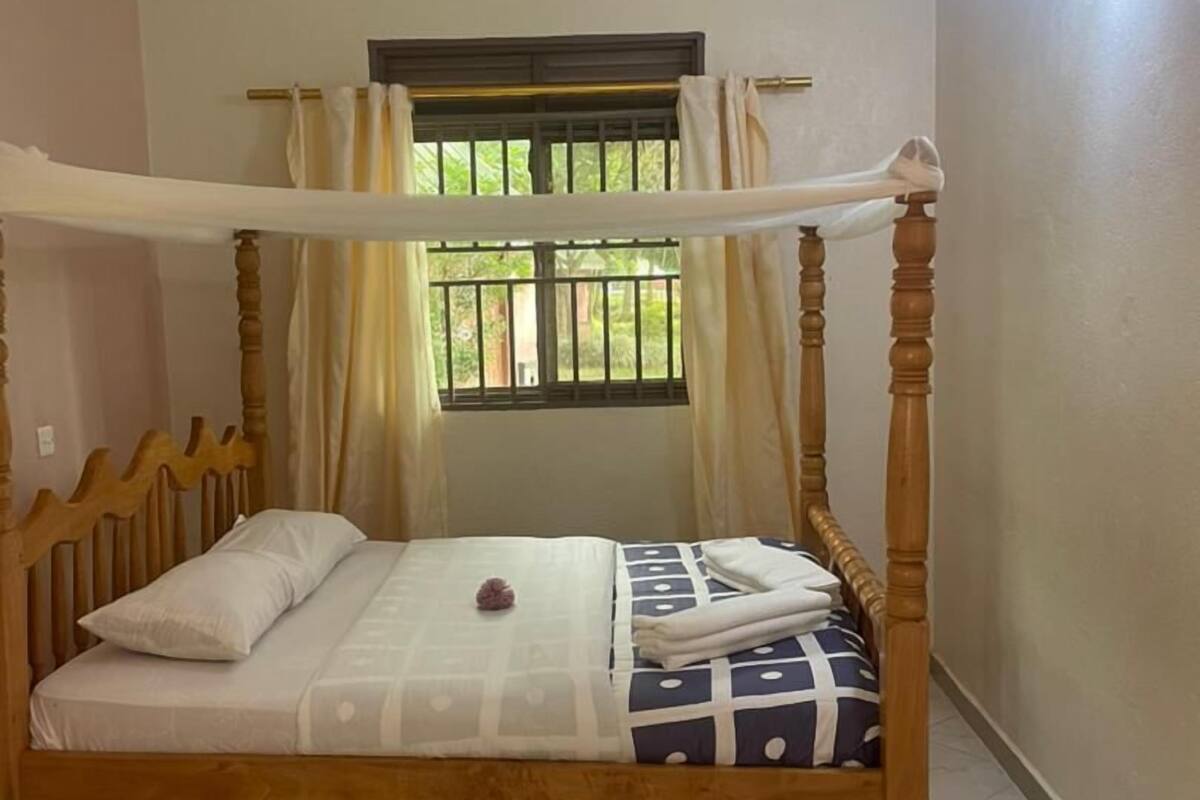 Een hemelbed met baldakijn, een raam met tralies en een hangende lamp.