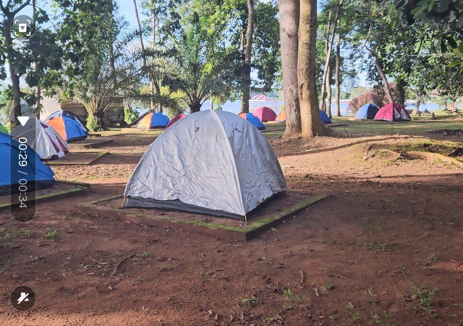 A campsite with multiple tents set up on a dirt ground surrounded by trees.