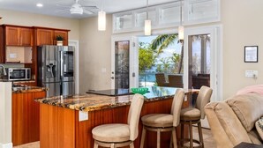 A kitchen with a central island, stainless steel appliances, and a view to the outdoors. - Big Island Aloha Pearl House 4 Bedroom Home (Kailua-Kona)