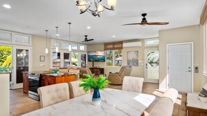 A spacious living area with a dining table, comfortable seating, a TV, and a ceiling fan. - Big Island Aloha Pearl House 4 Bedroom Home (Kailua-Kona)