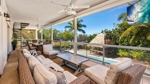 A spacious balcony with wicker furniture, a pool, and a view of the ocean. - Big Island Aloha Pearl House 4 Bedroom Home (Kailua-Kona)