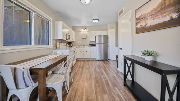 Een moderne keuken met witte kasten, een roestvrijstalen koelkast en een houten eettafel.