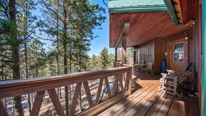 Une terrasse en bois avec une rambarde donnant sur une zone boisée.