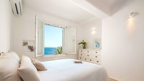 Un dormitorio con un ventanal grande, una cama, un tocador y un espejo.