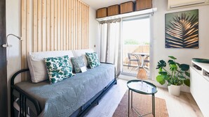 Een moderne slaapkamer met een bed, een klein tafeltje en een potplant.