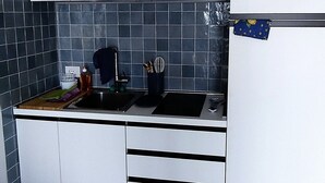 Eine Küche mit weißen Schränken, einer schwarzen Arbeitsplatte und einer gefliesten Rückwand.