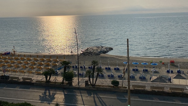 Ein Strand mit sonnigem Wasser, Sonnenschirmen und Liegestühlen.