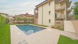 A modern building with a swimming pool, a covered outdoor area, and a staircase leading to an upper floor. - ApartmentsGarda - Residenza Eleonora 5 (Garda)