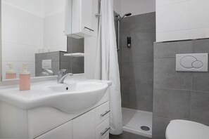 A modern bathroom with a white sink, mirror, and shower. - Schöne Apartments in Bad Rothenfelde (Bad Rothenfelde)
