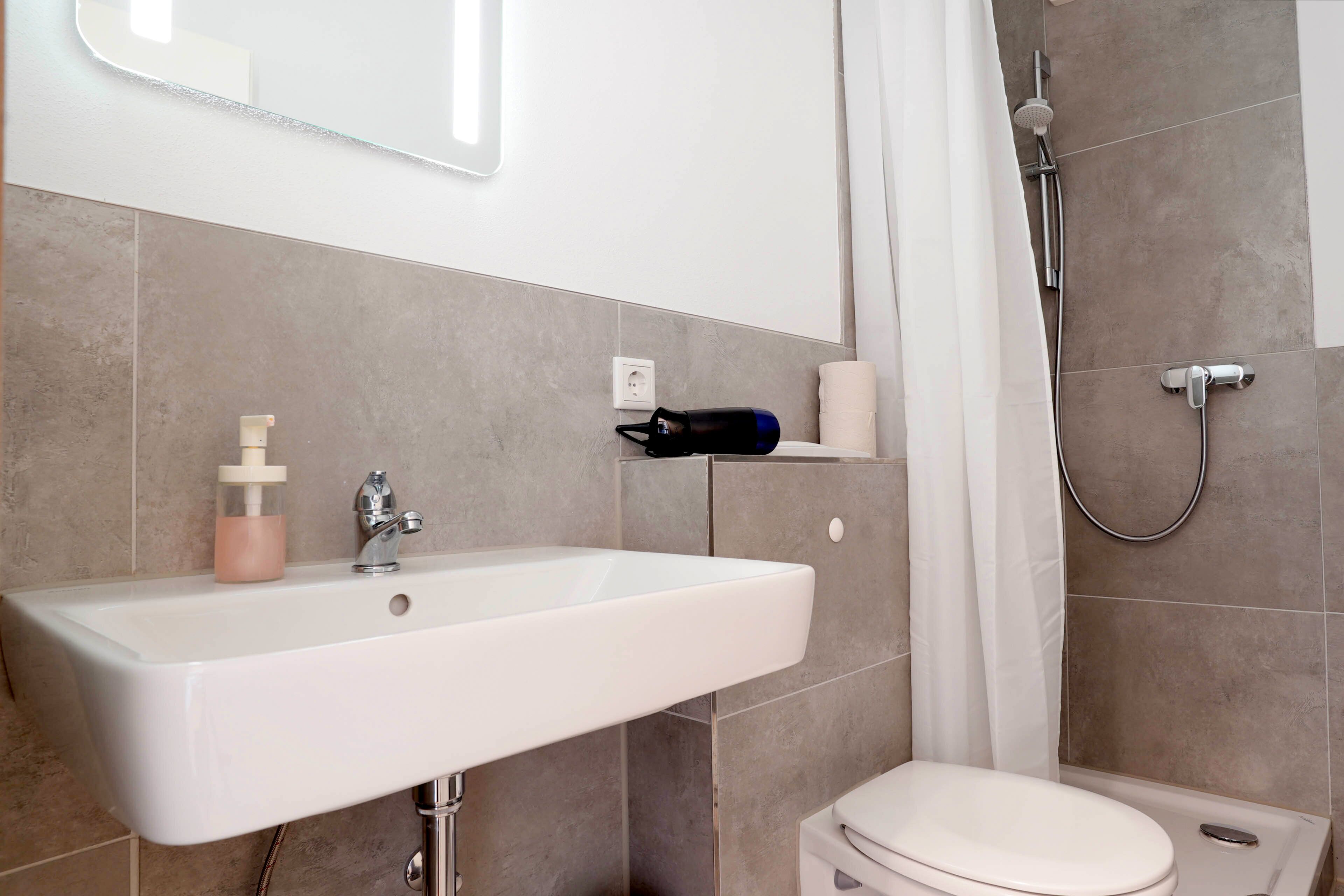 A bathroom with a white sink, a toilet, and a shower.