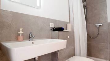 A bathroom with a white sink, a toilet, and a shower.