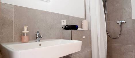 Un baño con lavamanos blanco, inodoro y ducha.