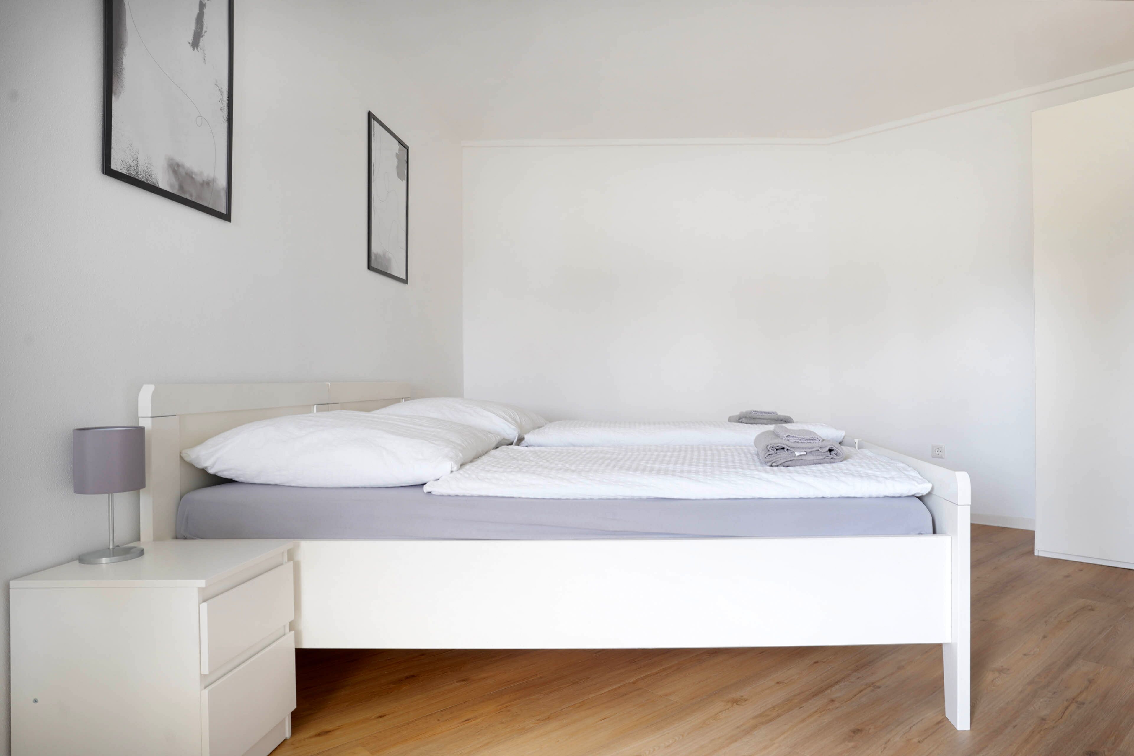 Une chambre à coucher au style minimaliste, avec un lit, une table de chevet et une lampe.