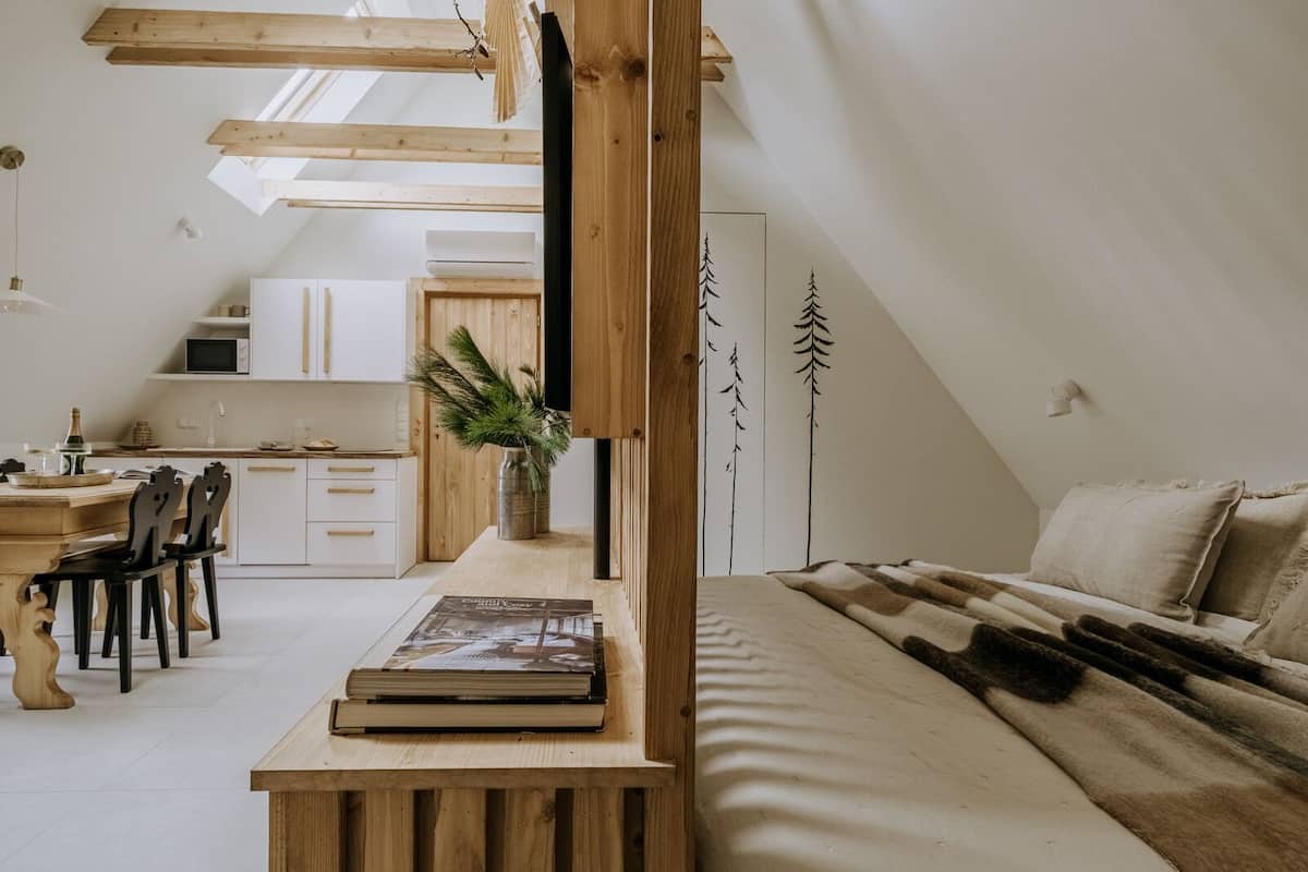 Un dormitorio tipo loft acogedor con techo inclinado, un escritorio de madera, una zona de comedor y una cocina.