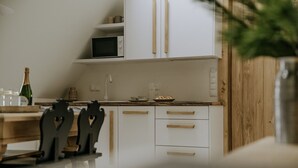 Une cuisine moderne avec des meubles blancs, un four à micro-ondes et un plan de travail en bois.