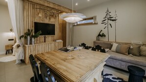 Un salon moderne avec une table à manger en bois, un canapé et un téléviseur fixé à un mur en bois.