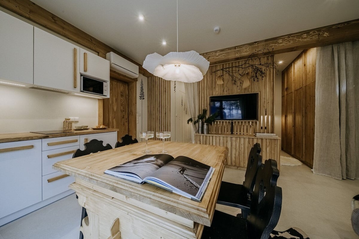 Una cocina moderna con armarios blancos, una mesa de comedor de madera y un ventanal grande.