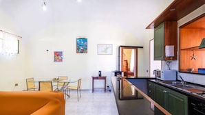 A compact kitchen with green cabinets, a dining area with a glass table and chairs, and a bright orange sofa. - Da Procida 97 - Two Bedroom Apartment, Sleeps 5 (Procida)