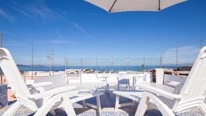 A terrace with white lounge chairs and a tiled floor, overlooking the sea. - Da Procida 97 - Two Bedroom Apartment, Sleeps 5 (Procida)