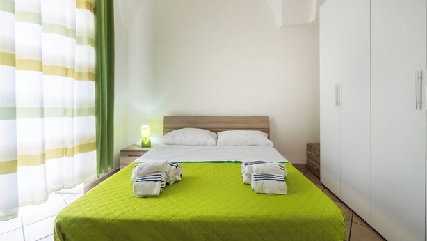 A hotel room with a bed, a nightstand, a lamp, and a wardrobe. - Isba Da Procida - Two Bedroom Apartment, Sleeps 5 (Procida)