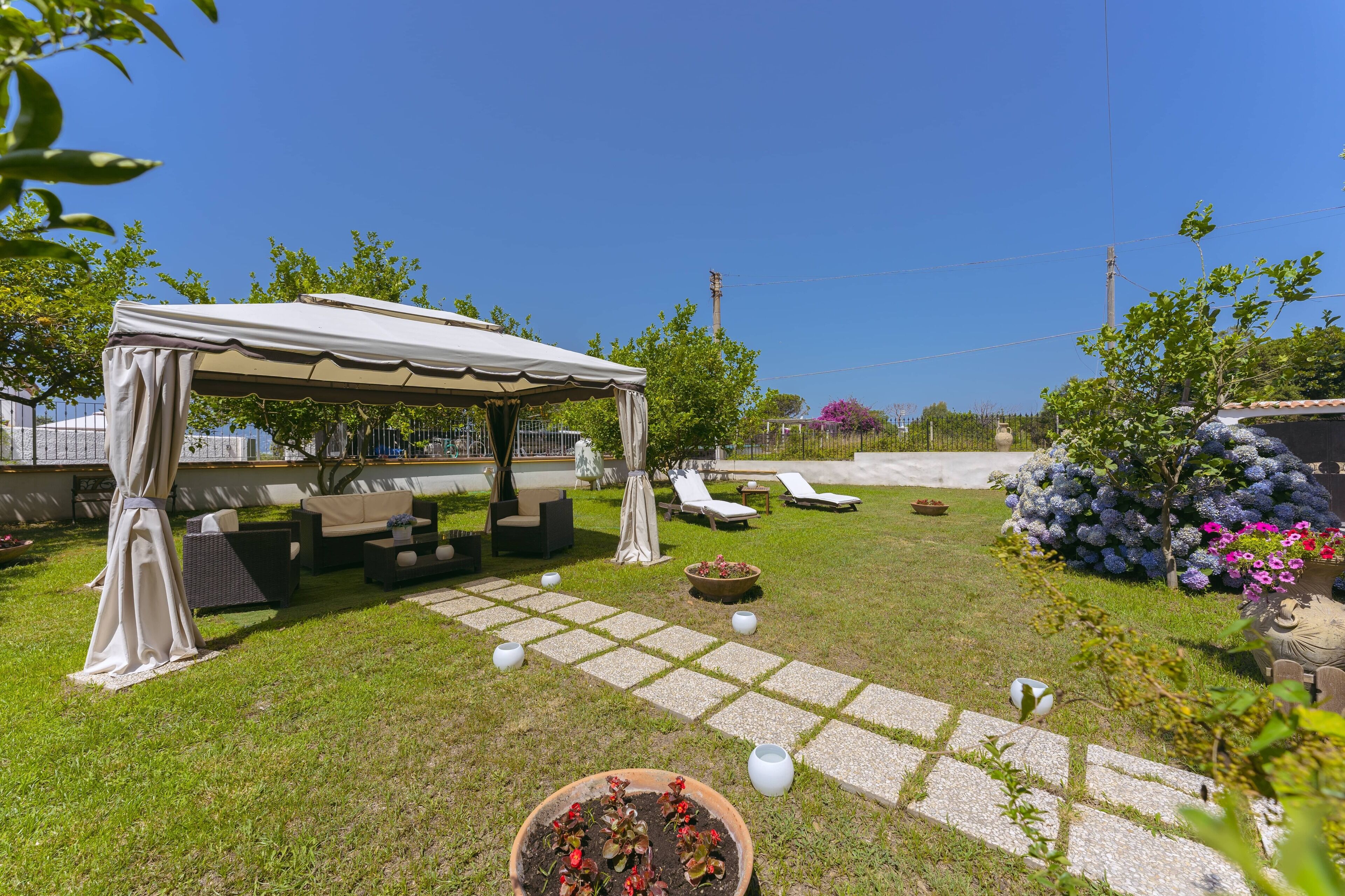 A patio area with a covered seating area, outdoor furniture, and potted plants.