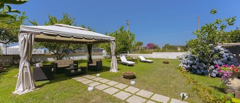 A patio area with a covered seating area, outdoor furniture, and potted plants.