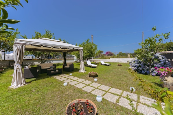 A patio area with a covered seating area, outdoor furniture, and potted plants.