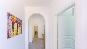 A hallway with a tiled floor, a white door, and a painting on the wall. - Pilòn 26 - Two Bedroom Apartment, Sleeps 5 (Procida)
