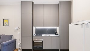 A compact kitchen with a built-in oven, a sink, and a coffee maker.
