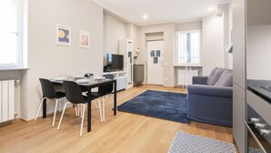 A modern apartment with a dining area, kitchen, and living space.