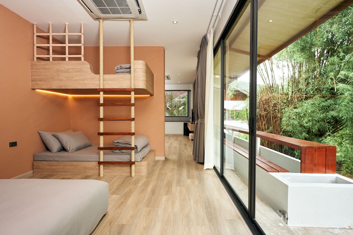 Un dormitorio moderno con cama de altillo, estanterías empotradas y un balcón con vistas a bambú.